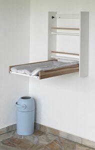 Das Bild zeigt einen Wand-Wickeltisch zum Aufklappen mit Windel-Eimer.