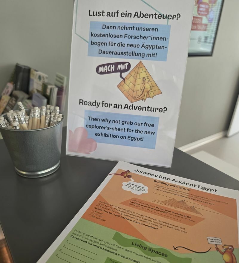 Auslage einer Kinder-Rallye an der Museumkasse mit Infoschild und Stiftebox.